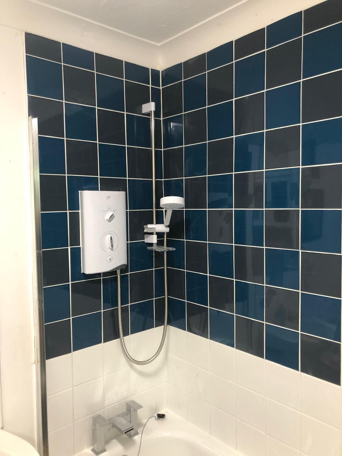 Bathroom refit in London with navy blue wall tiles and a new Mira electric shower installed by Refurb Squad