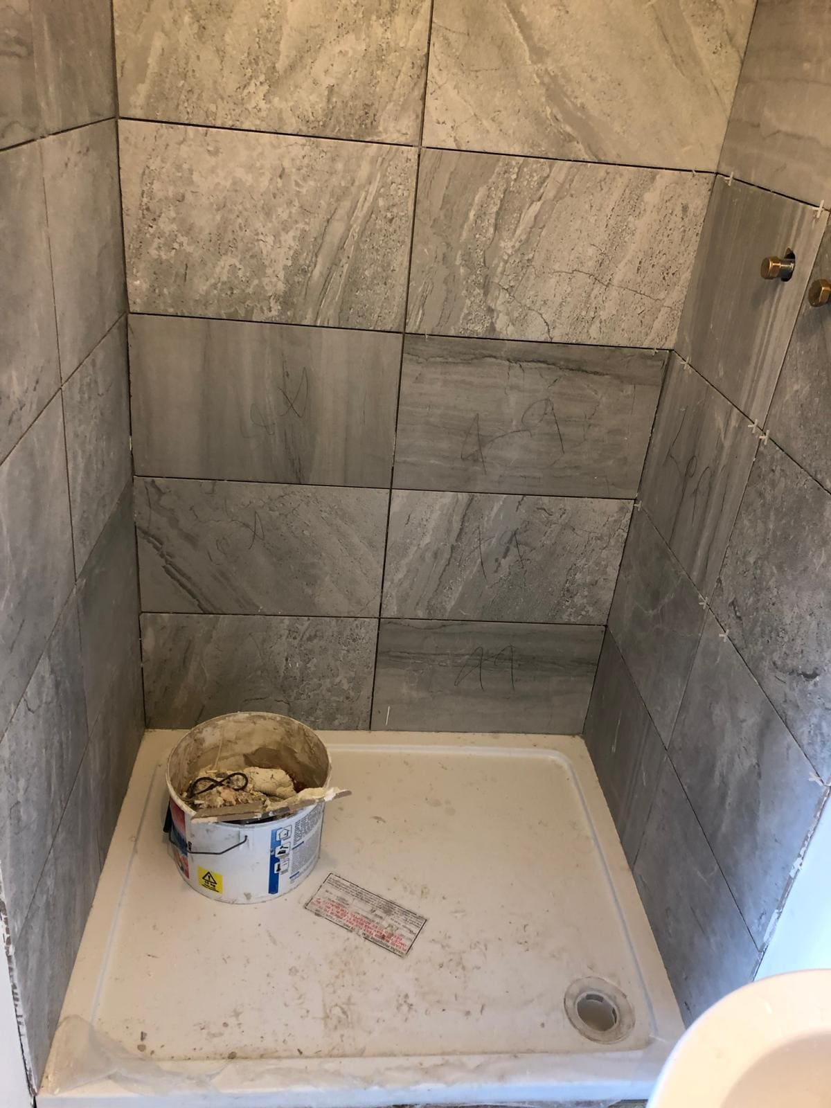 Marble-effect grey tiled shower enclosure being installed in a London bathroom