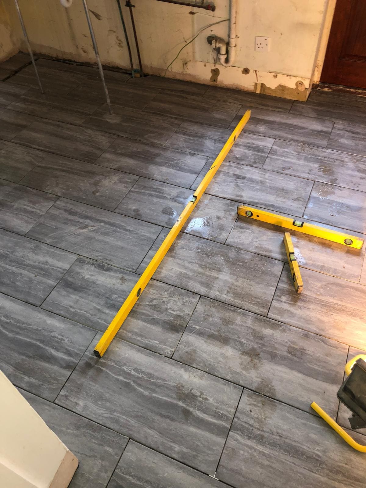 Completed grey stone-effect kitchen floor tiling in a London property by Refurb Squad